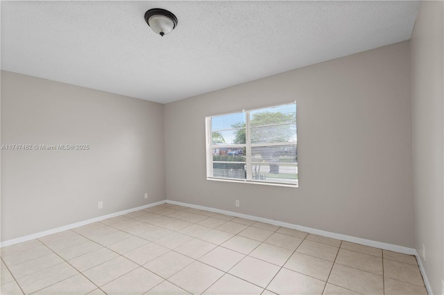 spare room featuring a textured ceiling and baseboards