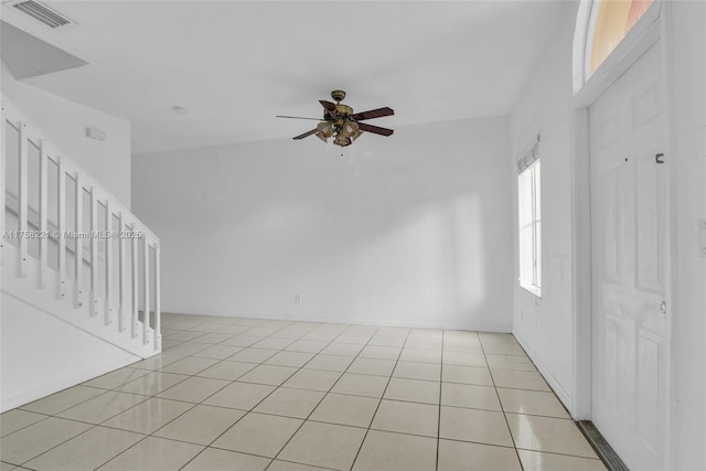 empty room featuring ceiling fan, light tile patterned floors, stairs, and visible vents