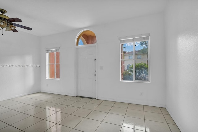 empty room with baseboards, a ceiling fan, and light tile patterned flooring