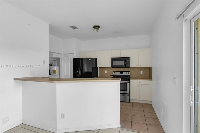 kitchen featuring light tile patterned floors, tasteful backsplash, a peninsula, cream cabinetry, and black appliances