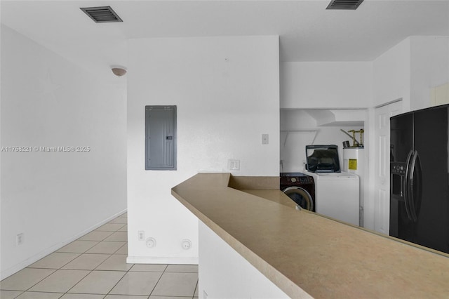 kitchen with light tile patterned floors, visible vents, black fridge with ice dispenser, washing machine and dryer, and electric panel