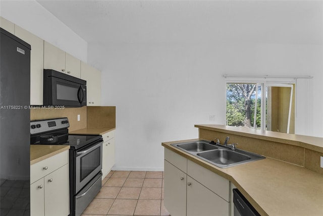 kitchen with black appliances, light countertops, a sink, and light tile patterned flooring