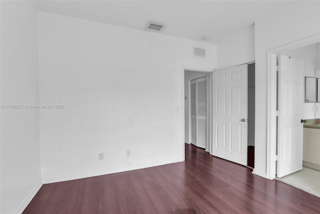 unfurnished bedroom featuring visible vents, baseboards, and wood finished floors