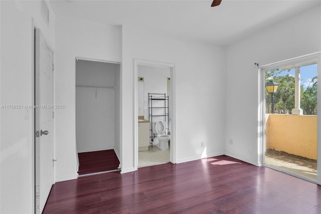 unfurnished bedroom featuring baseboards, connected bathroom, visible vents, and wood finished floors