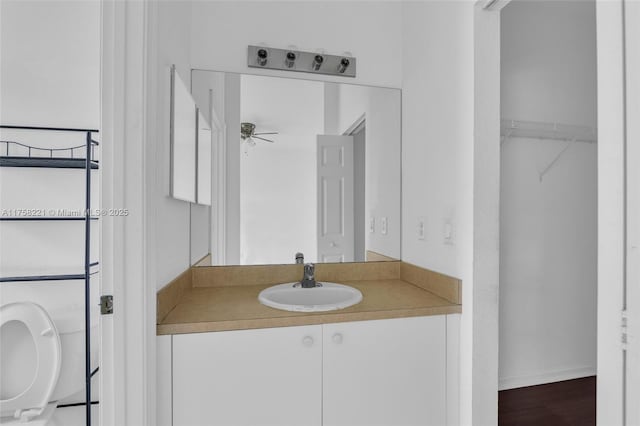 bathroom featuring ceiling fan, a spacious closet, and vanity