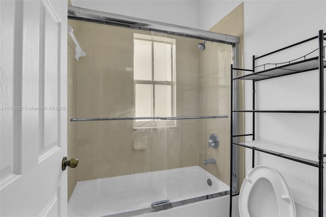 full bathroom featuring combined bath / shower with glass door and toilet