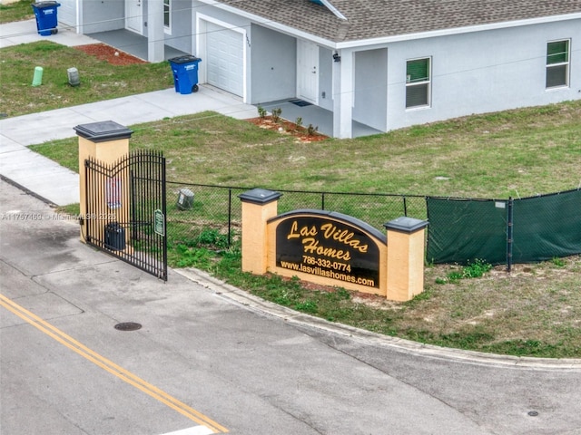 community / neighborhood sign featuring an attached garage, a yard, concrete driveway, and fence
