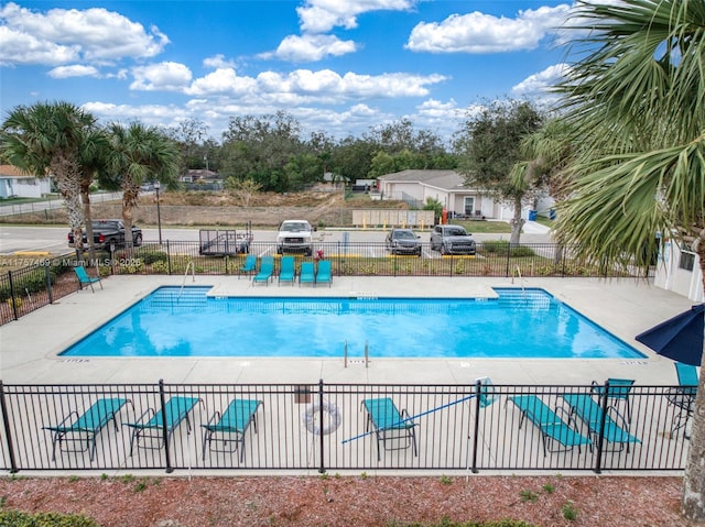 community pool with a patio area and fence