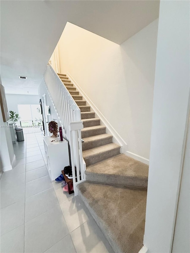 staircase with baseboards, visible vents, and tile patterned floors