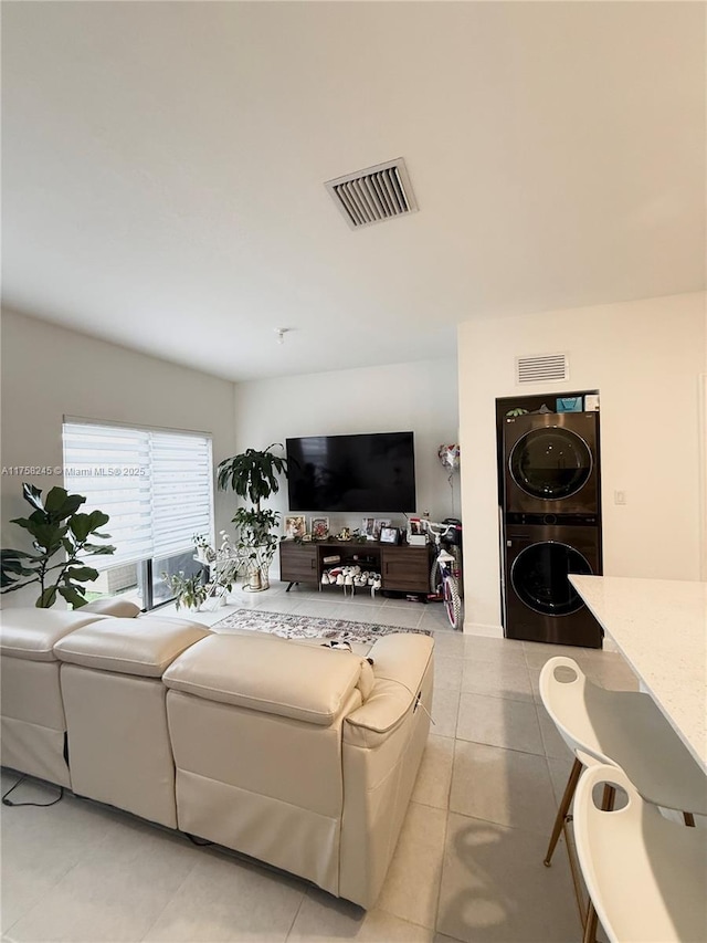 living area featuring light tile patterned floors, visible vents, and stacked washer / dryer