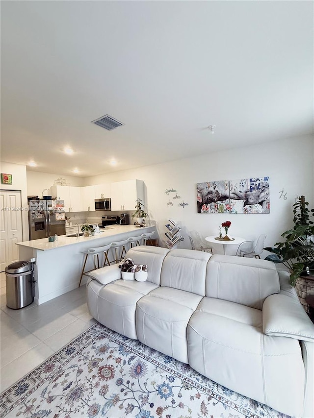 living area with visible vents and light tile patterned floors