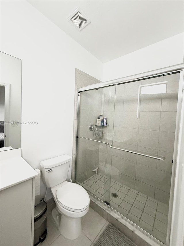 bathroom featuring toilet, vanity, visible vents, tile patterned floors, and a stall shower