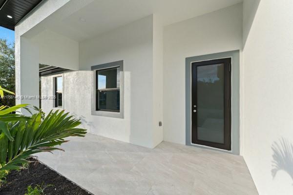 3318 9th St SW, Lehigh Acres, FL 33976 - entrance to property with a patio and stucco siding