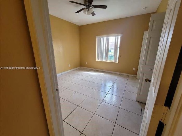 spare room with light tile patterned floors, ceiling fan, and baseboards