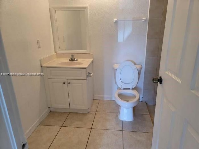 bathroom with toilet, vanity, baseboards, and tile patterned floors