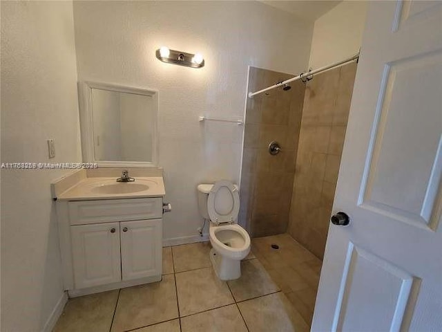 full bathroom featuring baseboards, toilet, tile patterned flooring, a tile shower, and vanity