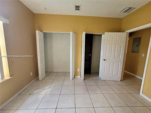 unfurnished bedroom featuring electric panel, visible vents, and light tile patterned floors