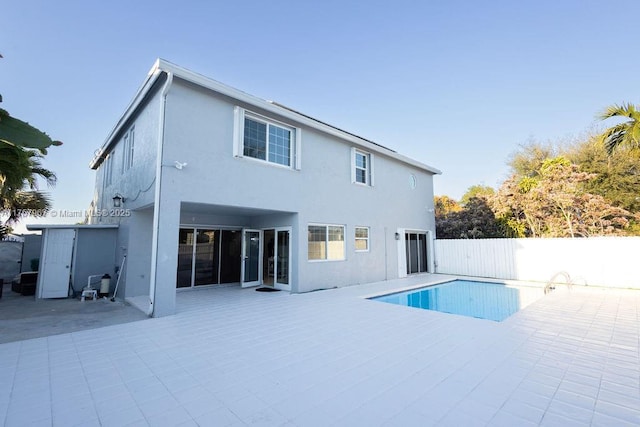 rear view of house with a patio area, a fenced backyard, a fenced in pool, and stucco siding