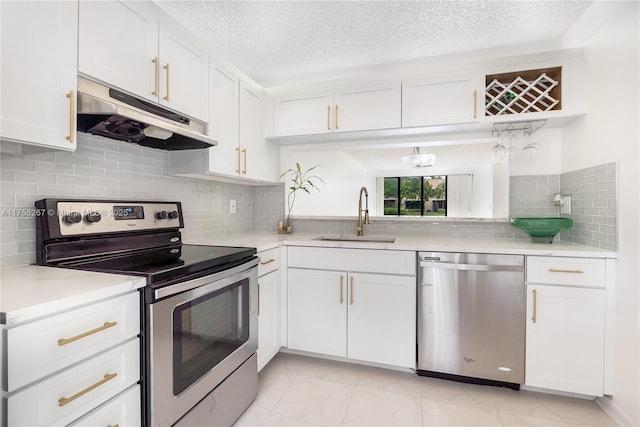 kitchen featuring appliances with stainless steel finishes, light countertops, a sink, and under cabinet range hood