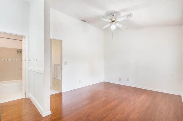 empty room with ceiling fan, a textured ceiling, visible vents, and wood finished floors