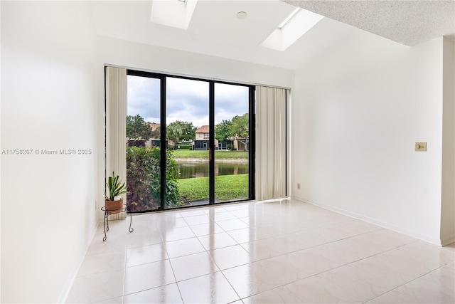 spare room with light tile patterned floors, a skylight, and baseboards