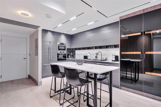 kitchen featuring electric panel, modern cabinets, a kitchen island, a breakfast bar, and a sink