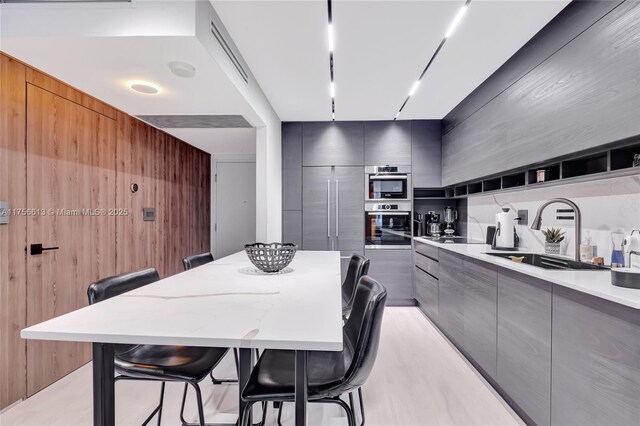 2301 Collins Ave Unit 432, Miami Beach, FL 33139 - kitchen with modern cabinets, gray cabinetry, a sink, and wooden walls