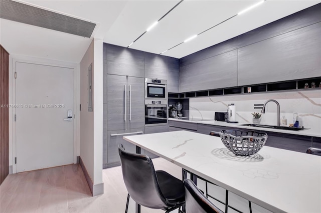 kitchen with visible vents, modern cabinets, a kitchen breakfast bar, built in refrigerator, and a sink