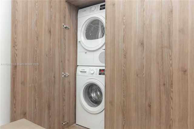 clothes washing area featuring stacked washer and dryer and laundry area