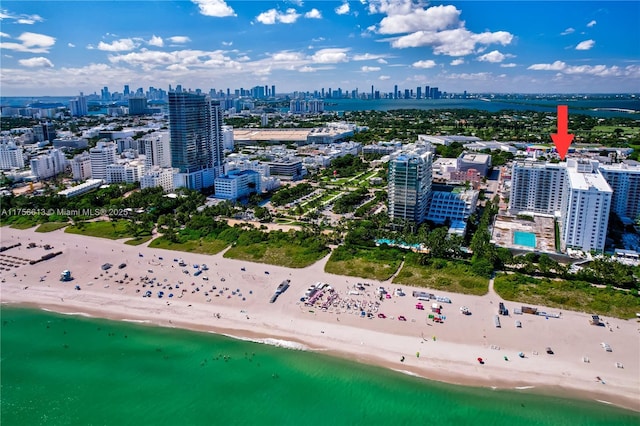 drone / aerial view featuring a water view, a view of city, and a beach view