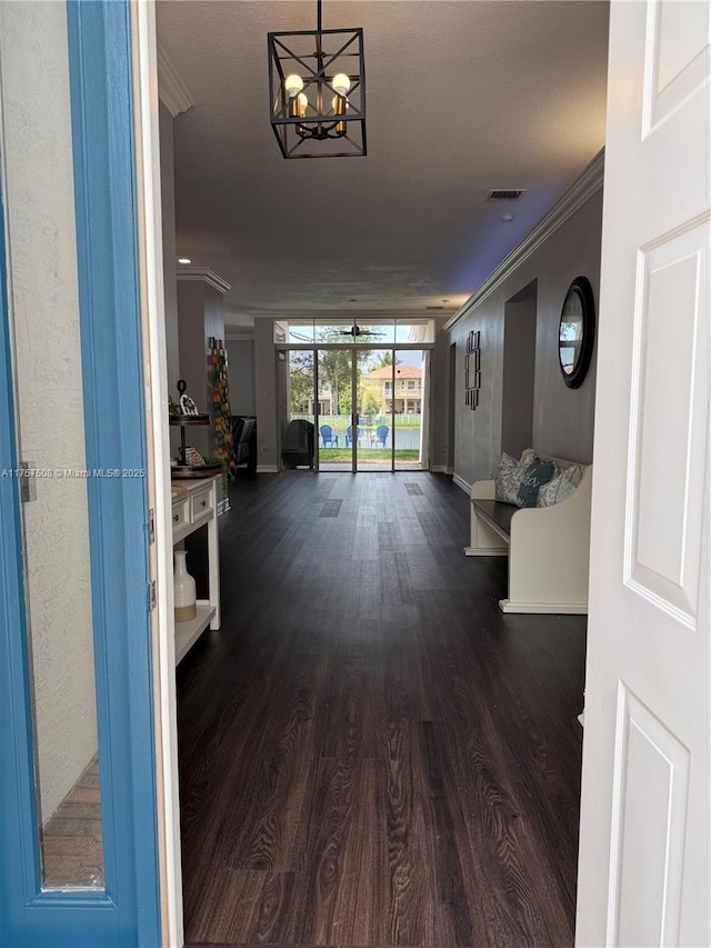 corridor with visible vents, a chandelier, dark wood-style flooring, and crown molding