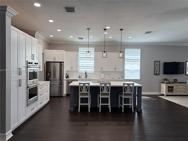 kitchen with stainless steel appliances, light countertops, a center island, and visible vents