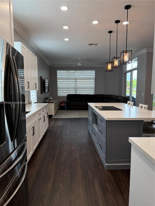 kitchen with black appliances, ornamental molding, light countertops, and visible vents