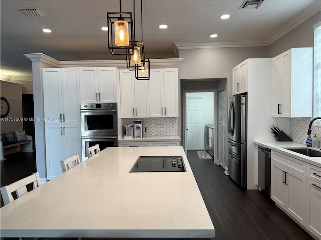 kitchen with visible vents, stainless steel appliances, crown molding, white cabinetry, and a sink