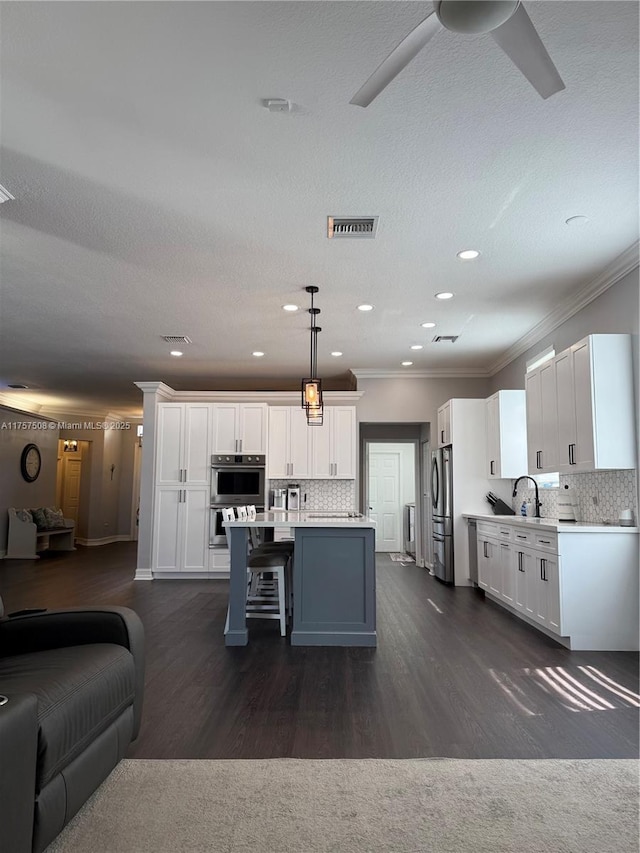 kitchen featuring white cabinets, appliances with stainless steel finishes, open floor plan, and light countertops