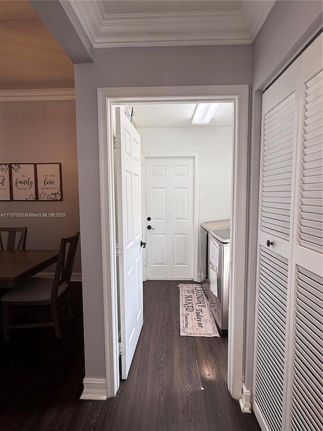 corridor with baseboards, ornamental molding, dark wood finished floors, and washer and dryer