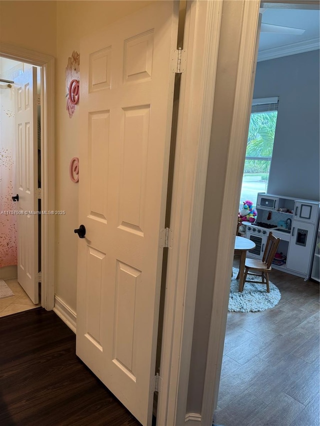 hallway with dark wood-style flooring, crown molding, and baseboards