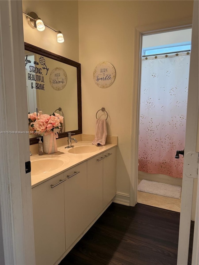 full bathroom with double vanity, shower / bath combo, a sink, and wood finished floors