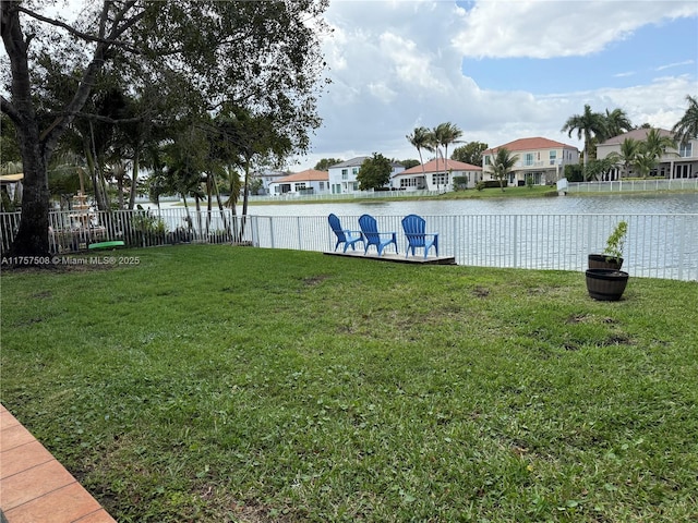 view of yard featuring a water view, a residential view, and fence