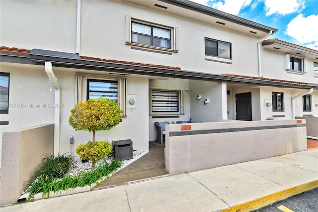 multi unit property featuring a tiled roof, central air condition unit, a fenced front yard, and stucco siding