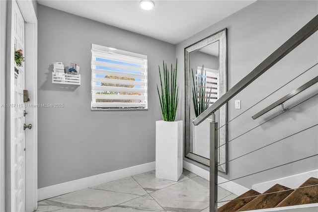 staircase featuring marble finish floor and baseboards