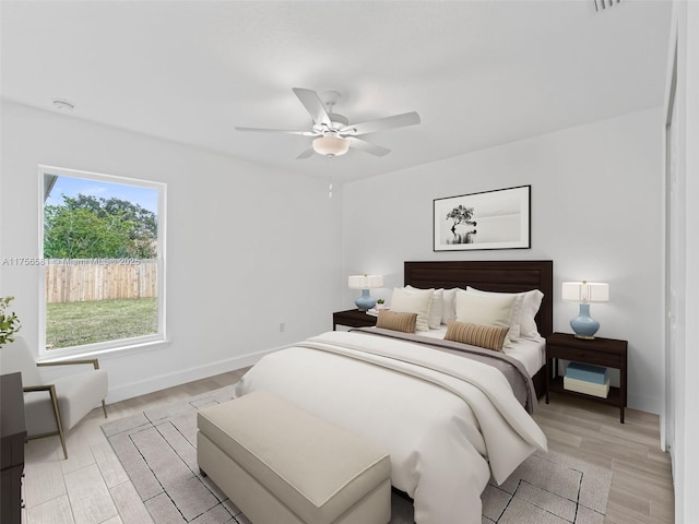 bedroom with ceiling fan, baseboards, and light wood-style floors