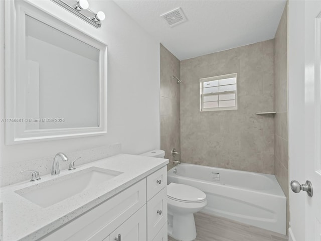 full bath with visible vents, toilet, washtub / shower combination, vanity, and wood finished floors