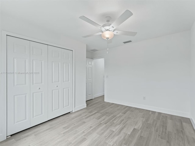 unfurnished bedroom featuring light wood finished floors, baseboards, visible vents, and a closet