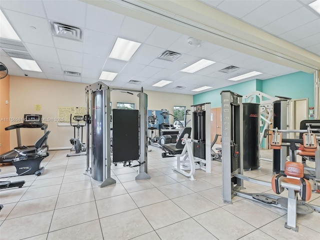 workout area featuring a paneled ceiling, visible vents, and light tile patterned flooring