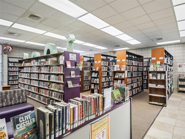 interior space with bookshelves, a paneled ceiling, and visible vents