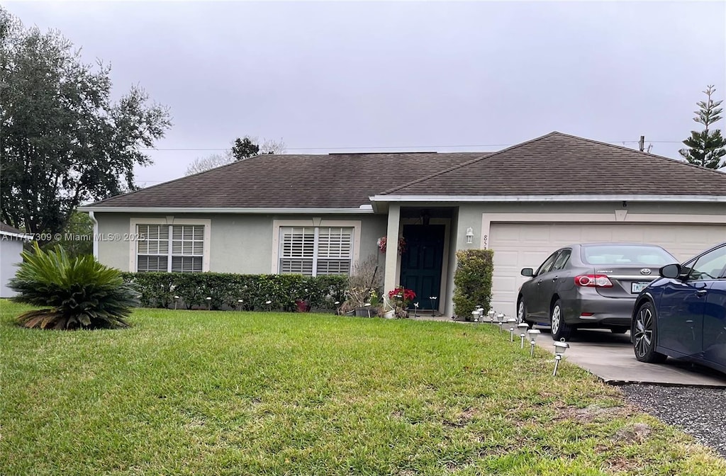 ranch-style house with a garage, a shingled roof, driveway, stucco siding, and a front yard