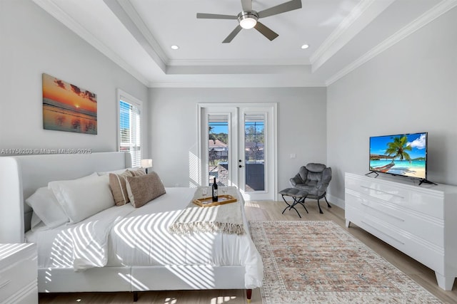 bedroom with access to exterior, ornamental molding, a raised ceiling, and wood finished floors