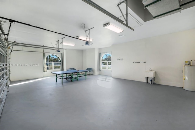 garage featuring a garage door opener, water heater, and a sink