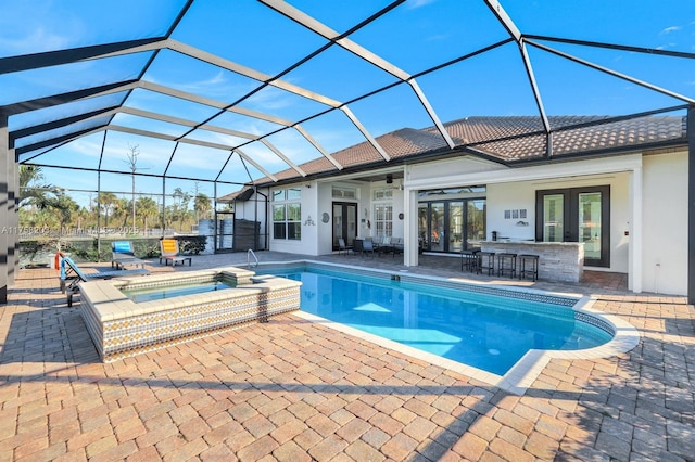 view of pool featuring french doors, a patio, outdoor dry bar, a pool with connected hot tub, and a lanai